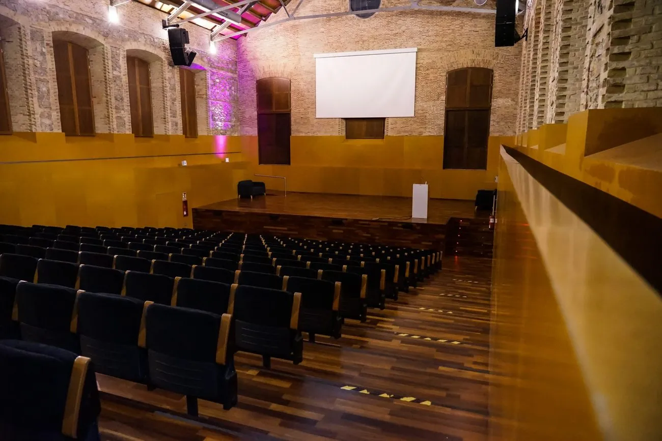 Salón montado en formato auditorio, con filas de butacas frente al escenario