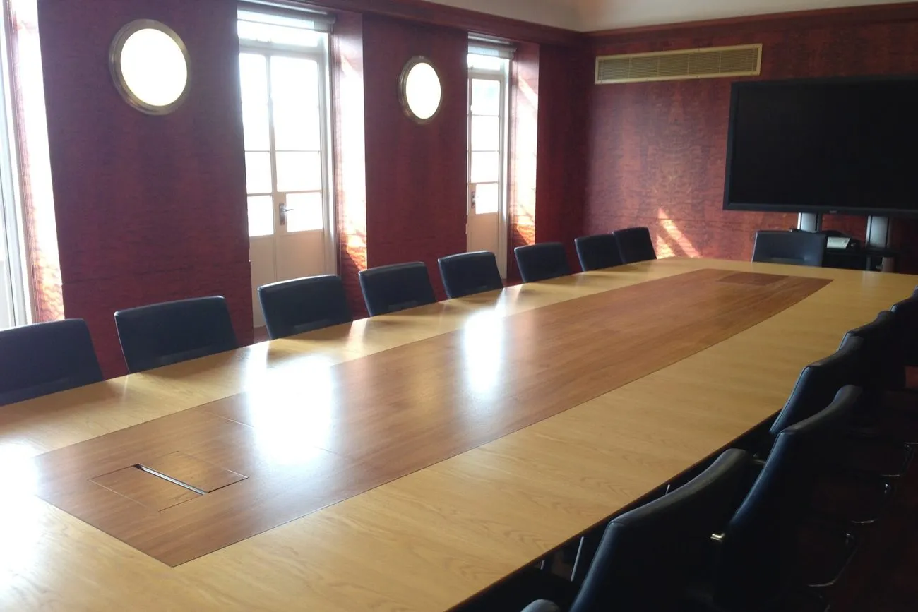 Sala de juntas con una mesa larga de madera y sillas alrededor