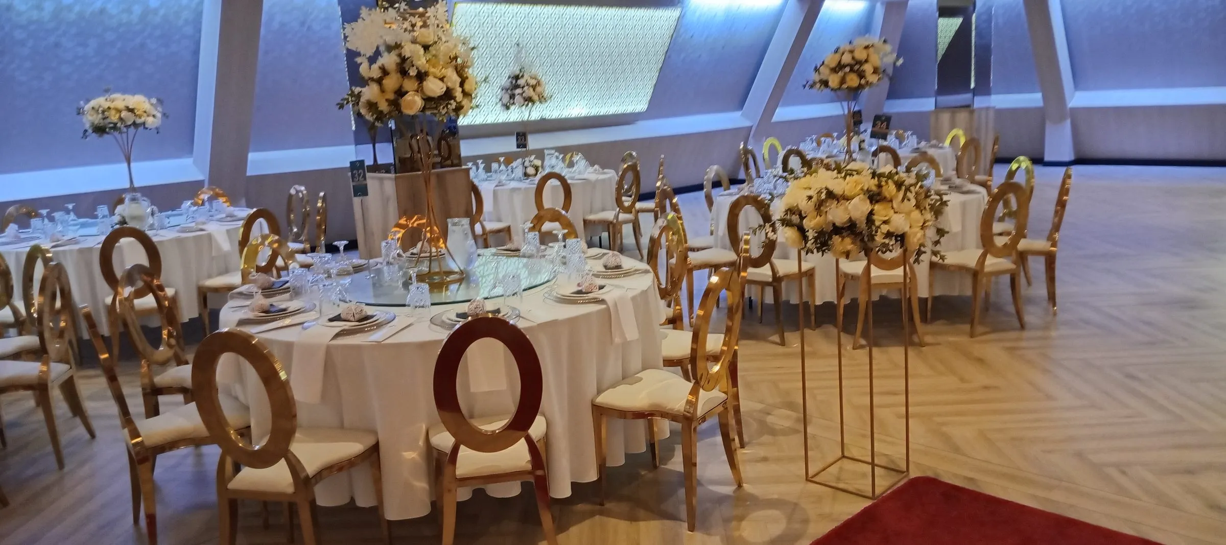 Salón principal montado con mesas redondas y centros de flores para una boda