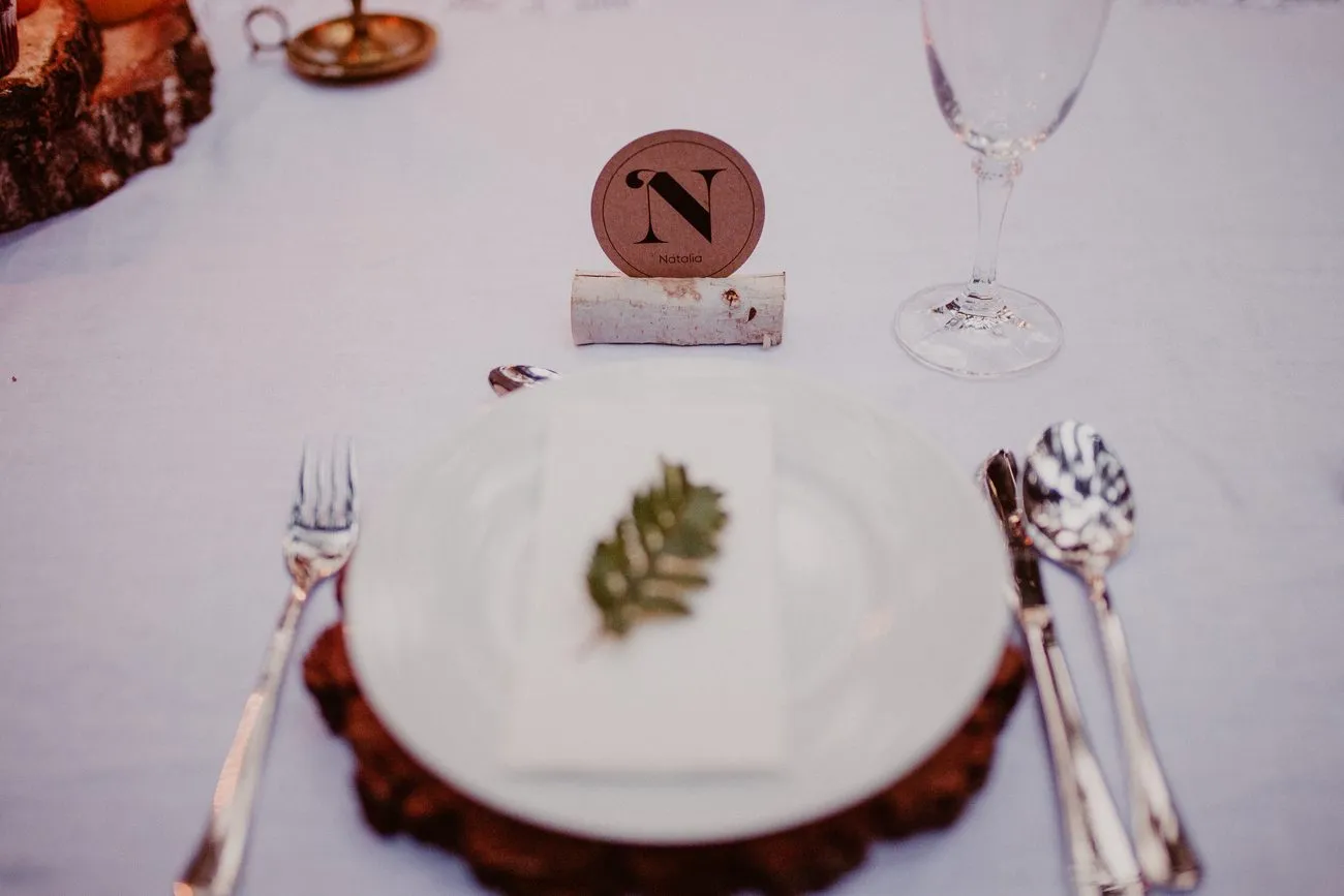 Detalle de un lugar en la mesa: plato, cubiertos, copa y tarjeta con el nombre