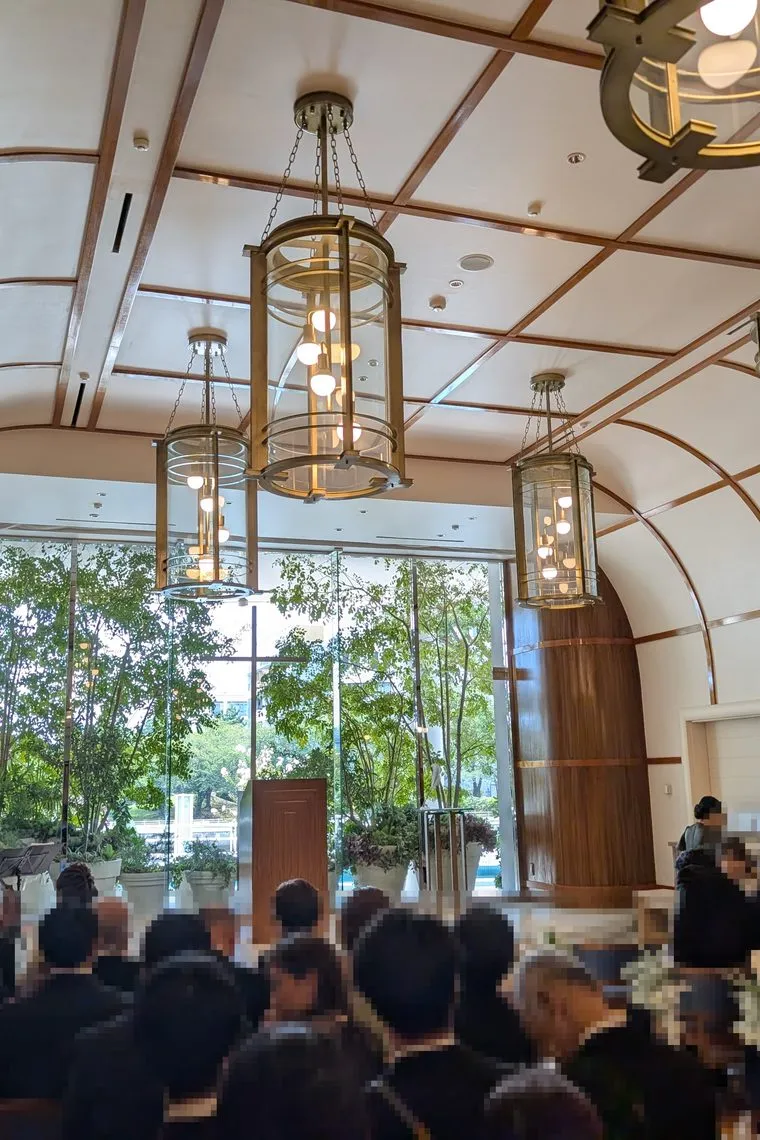 Salón montado para una ceremonia, con invitados sentados bajo el techo de cristal