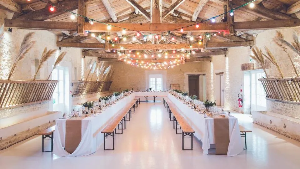 Salón de techos de madera con mesas largas y luces colgantes