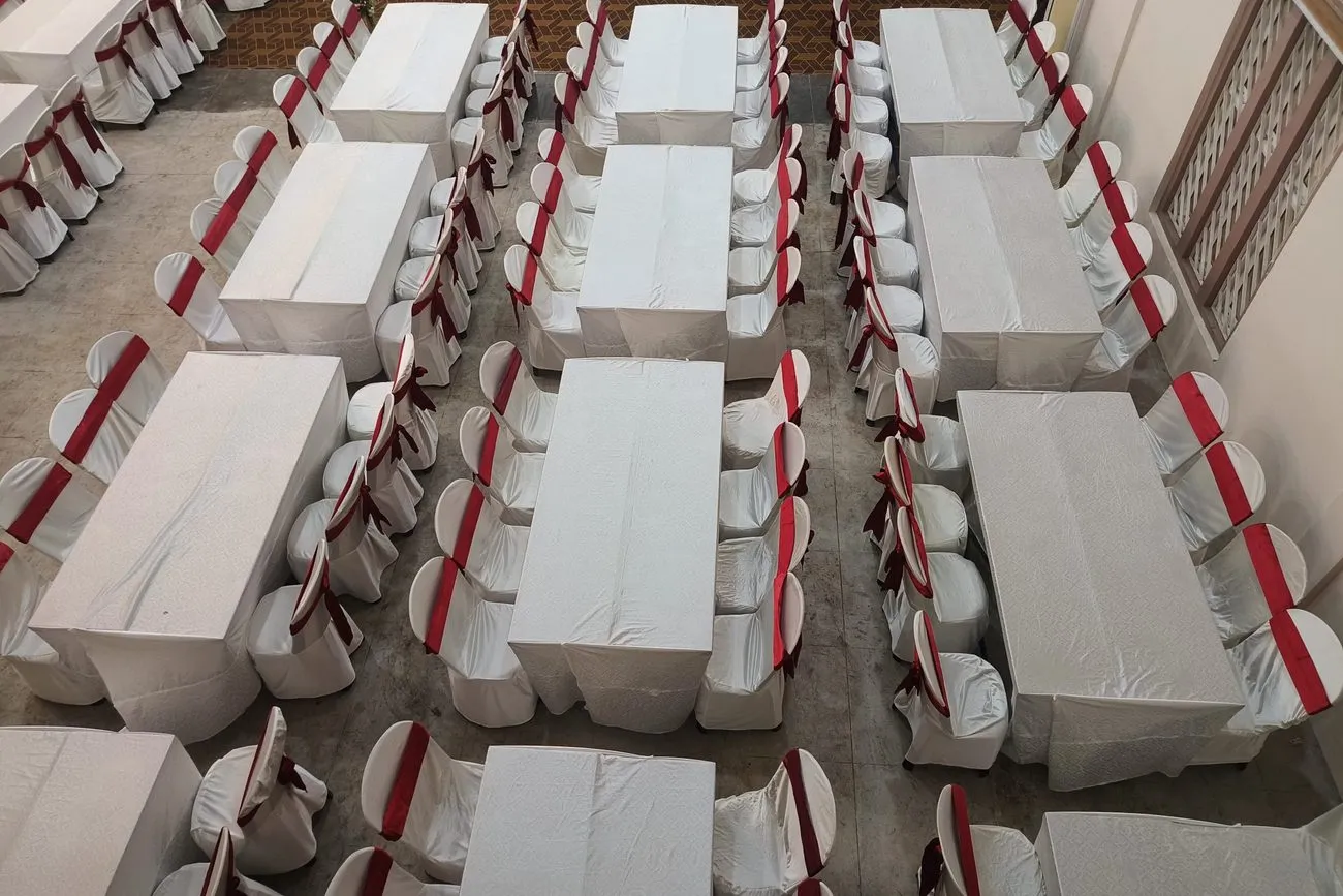 Filas de mesas largas vestidas con mantel blanco y sillas con moño